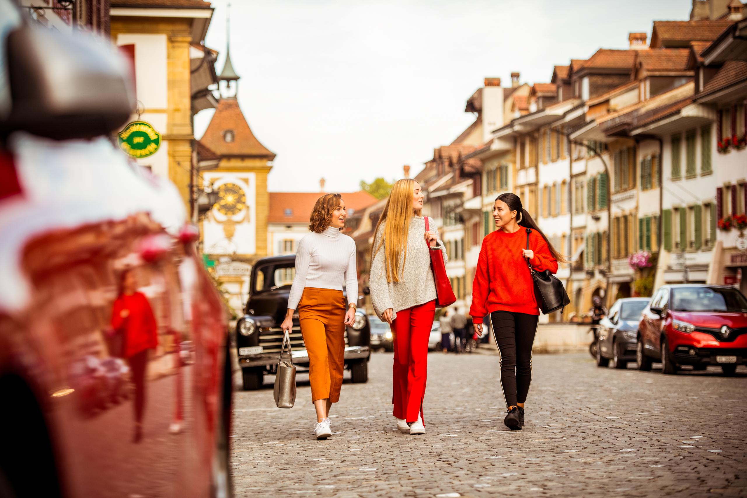Junge Mädchengruppe läuft durch Murten. Junge Frauen beim Shoppen in Murten mit moderner Kleidung. Murten Atstadt mit Pflastersteinen und Autos.