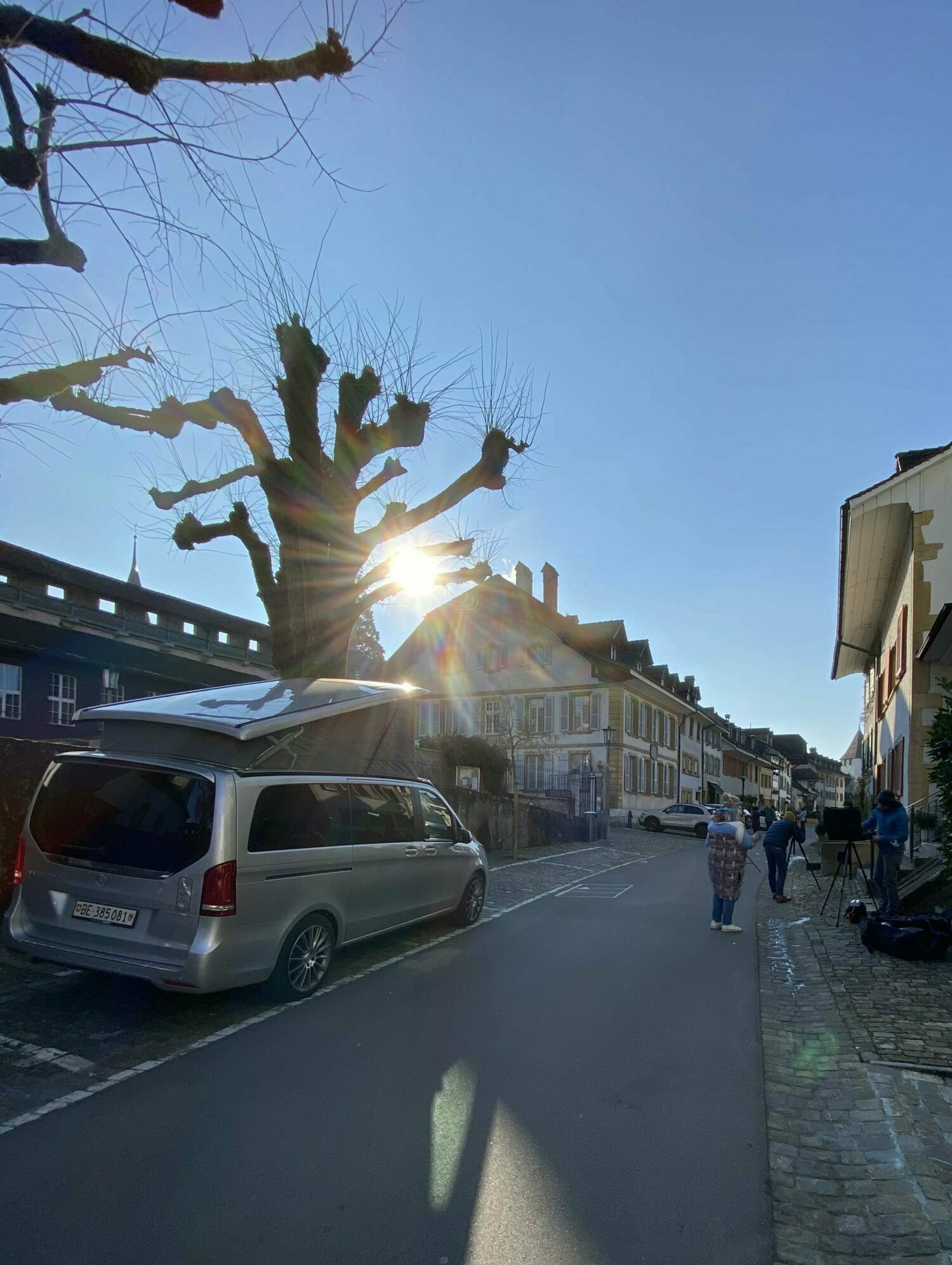 Silberner Mercedes Van in einer Gasse in Murten. Menschen beim Shooting.