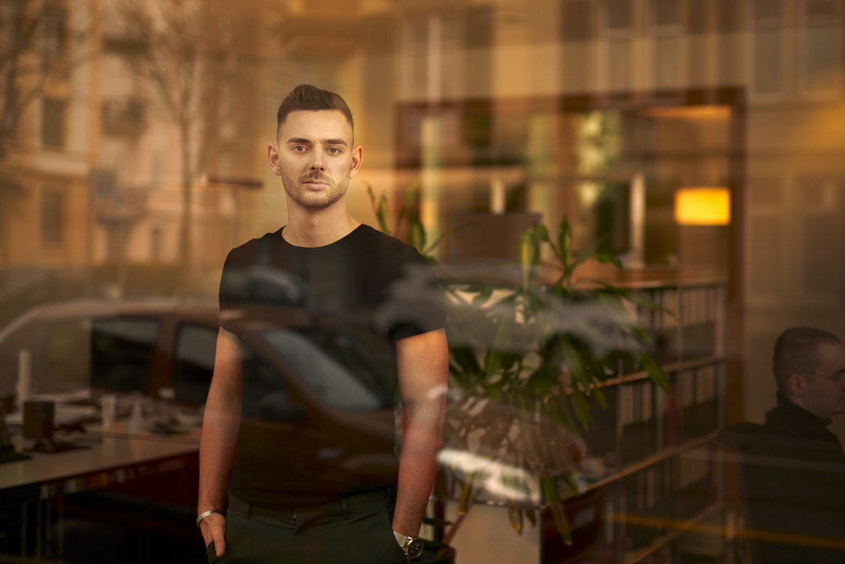 Mann steht im Büro mit Spiegelungseffekten.