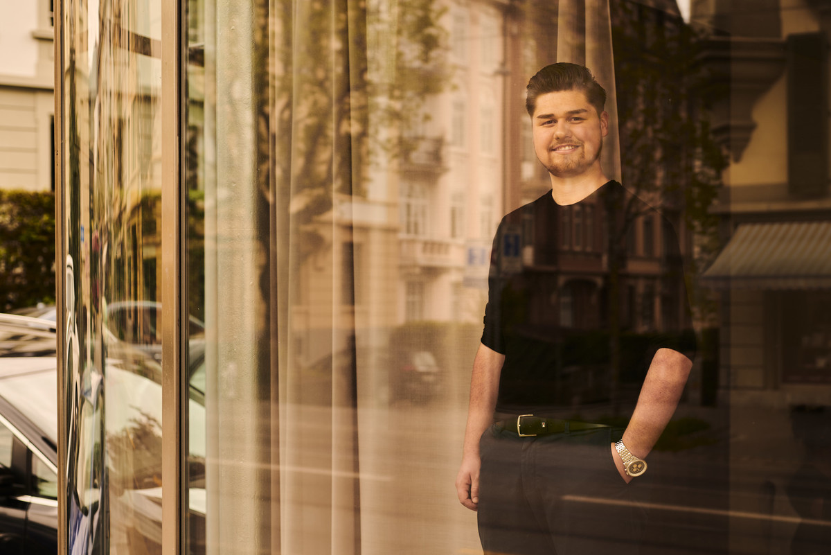 Mann steht im Büro mit Spiegelungseffekten. Aufnahme durch das Fenster.