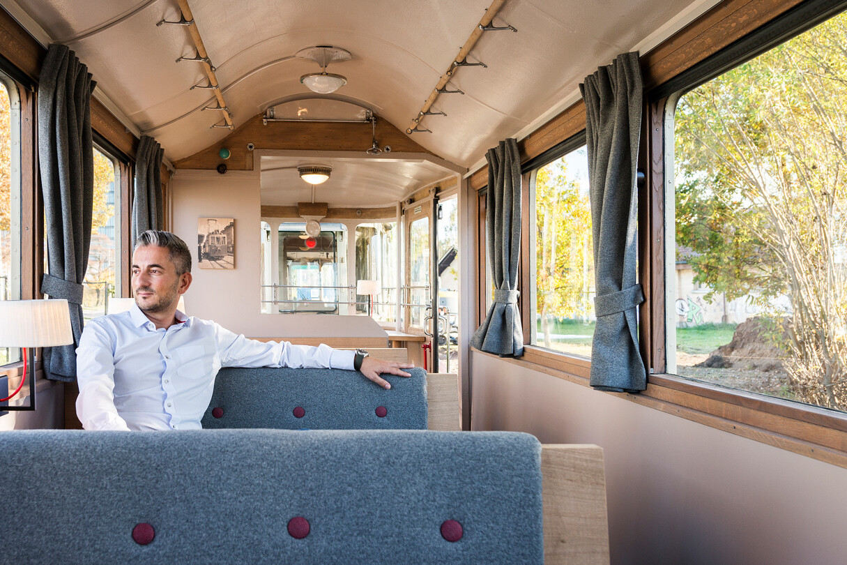 Mann sitzt im Notalgietram in Bern. Tram mit schönen Gardinen und Holzverkleidung.