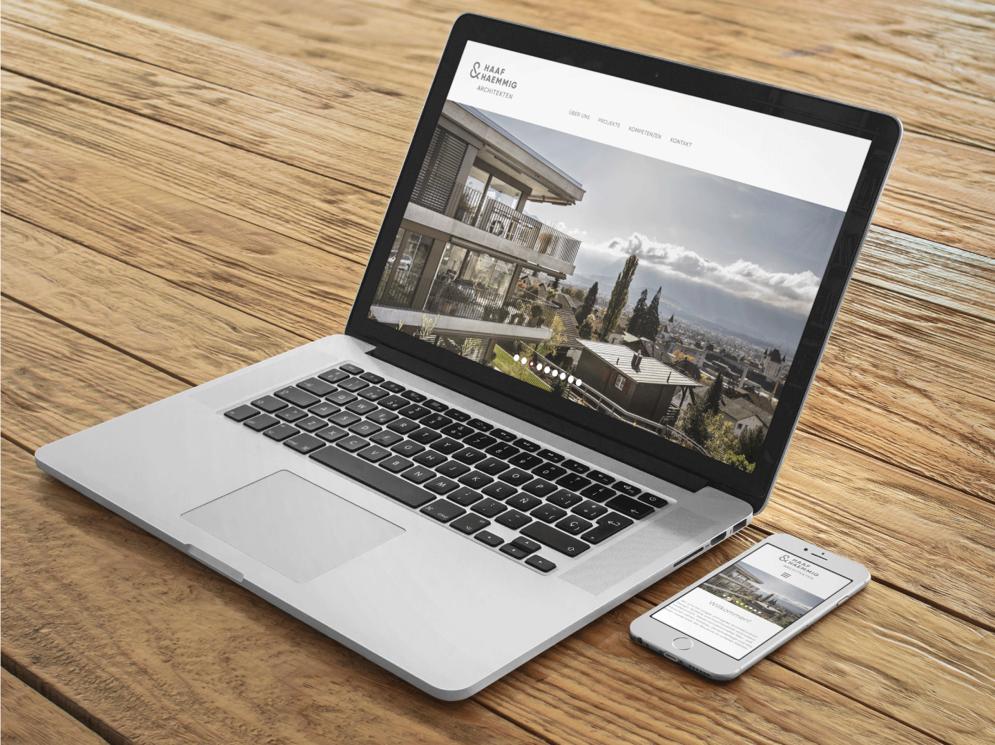 Laptop und Mobile Device mit Webseite Haaf und H&auml;mmig Architekten auf Holztisch.