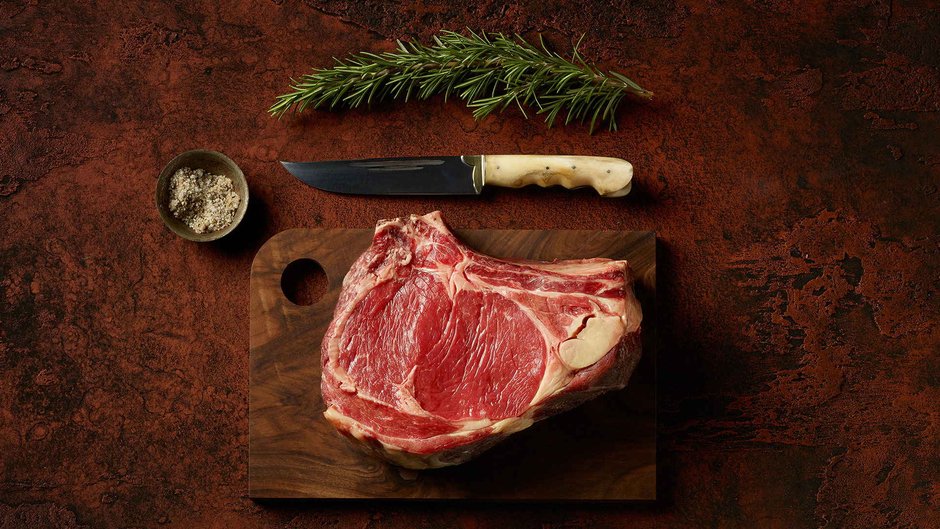 Steak auf Rostplatte mit Messer, Gewürzen und Kräutern