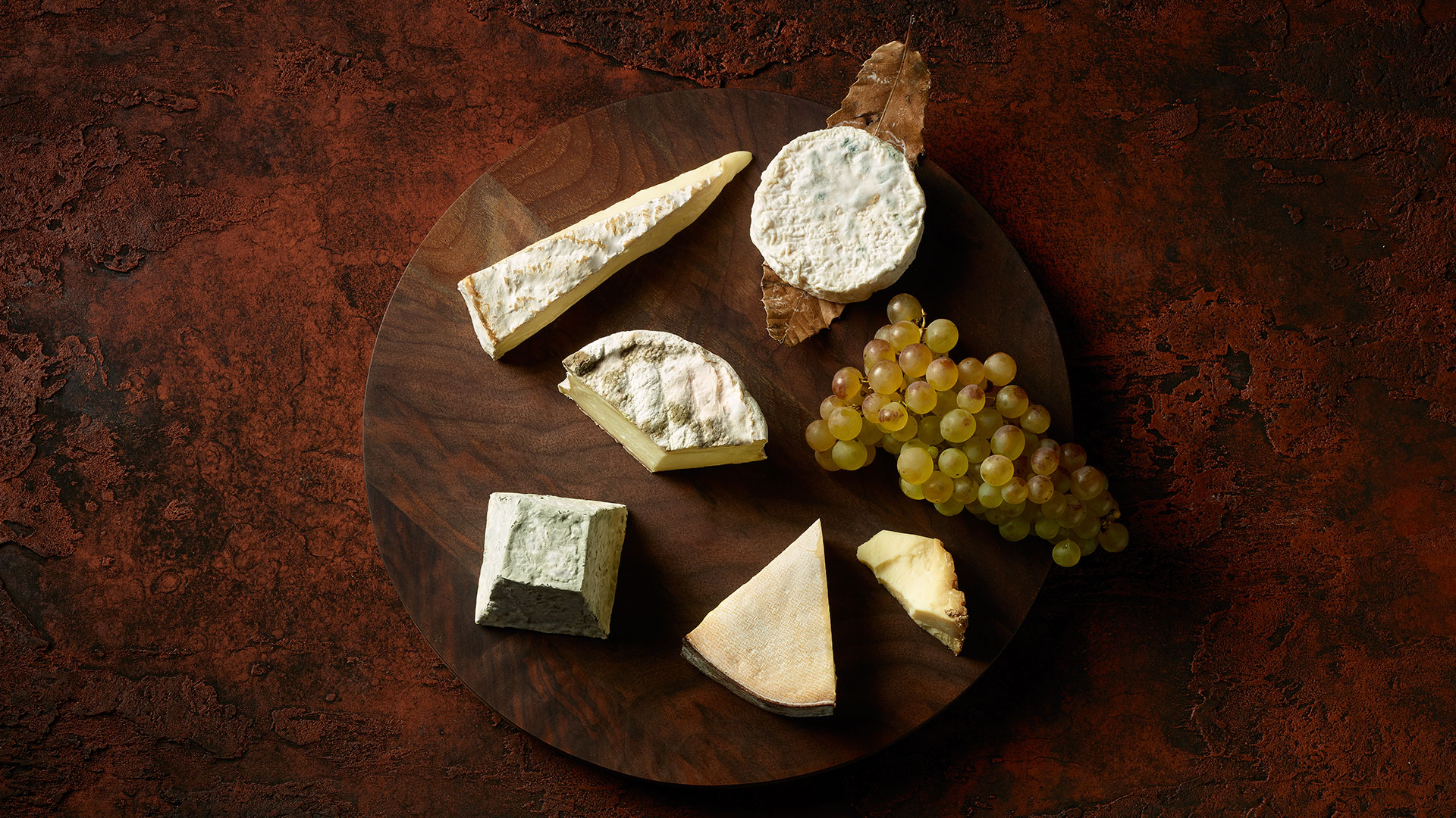 Weich Käseplatte auf rostigem Untergrund angerichtet mit Trauben
