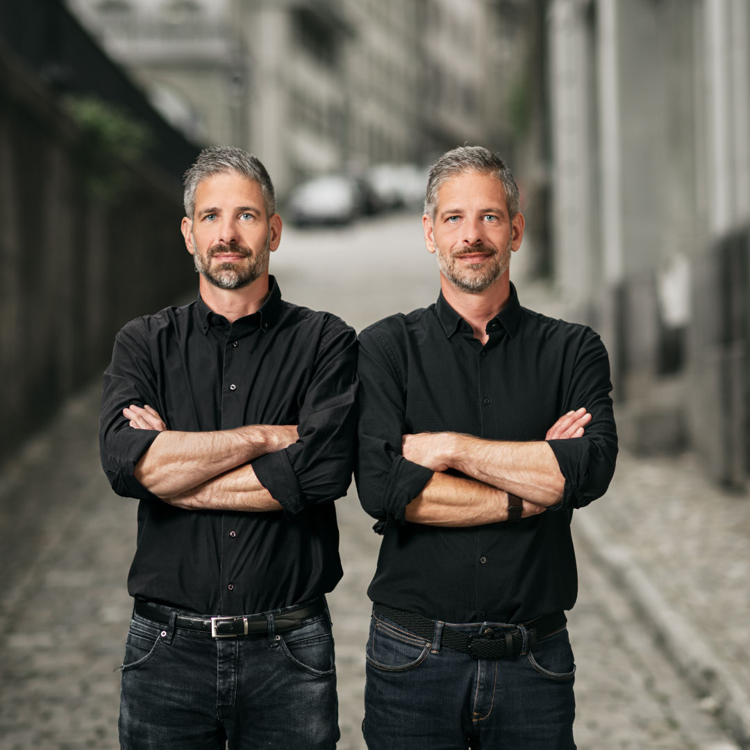 Männer stehen mit schwarzen Hemden in Freiburg. Zwillinge in der gleichen Position.