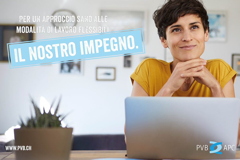 Frau sitzt am Computer. Frau mit kurzen Haaren und gelben T-Shirt l&auml;chelt sitzend am Tisch.