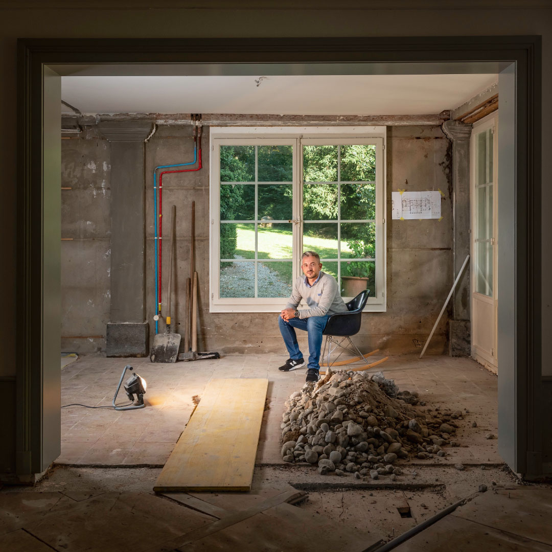 Mann sitzt in Mitte einer Baustelle. Architekt sitzt in Baustelle mit einem Schaukelstuhl