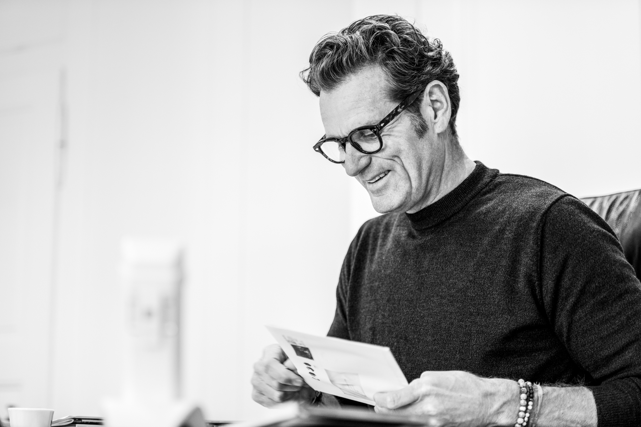 Thierry Laillard &ouml;ffnet Briefumschlag im B&uuml;ro. Schwarz Weiss Bild Mann mit Brille.