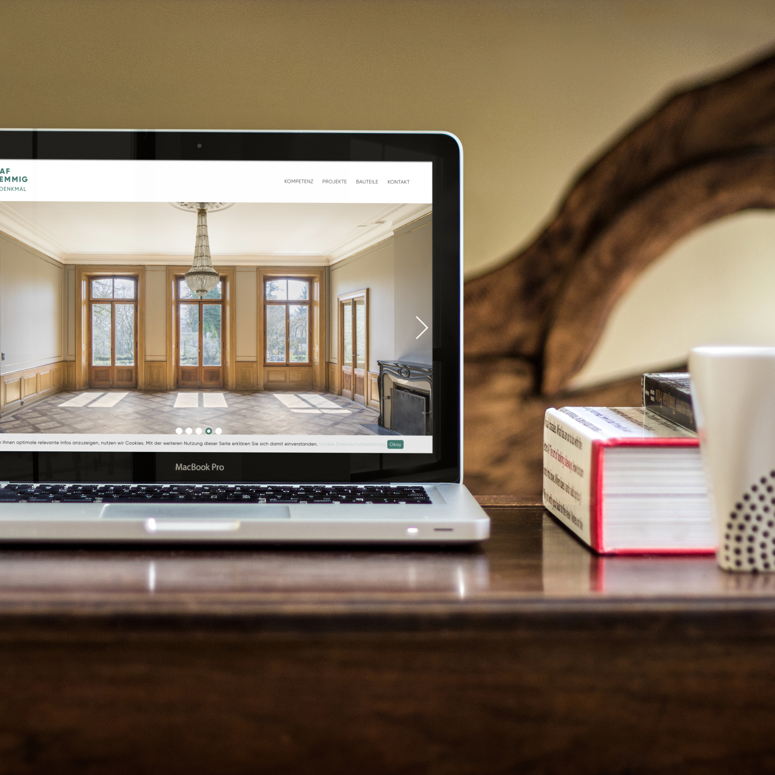 Webdesign einer Landingpage. Baudenkmalschutz Bern wird auf einem MAC Book angesehen. Laptop auf dem Tisch neben B&uuml;chern und Kaffee.