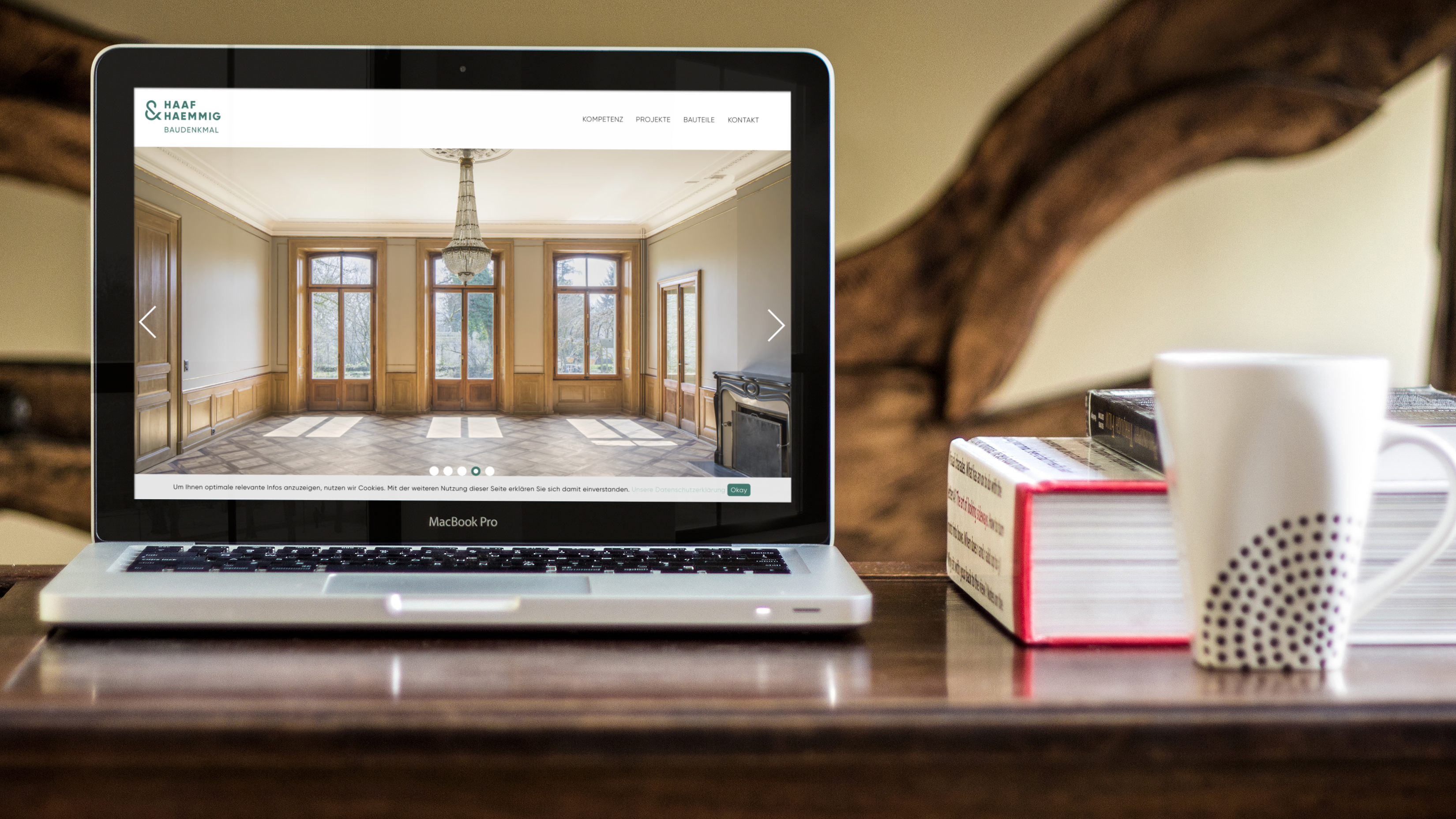 Webdesign einer Landingpage. Baudenkmalschutz Bern wird auf einem MAC Book angesehen. Laptop auf dem Tisch neben B&uuml;chern und Kaffee.