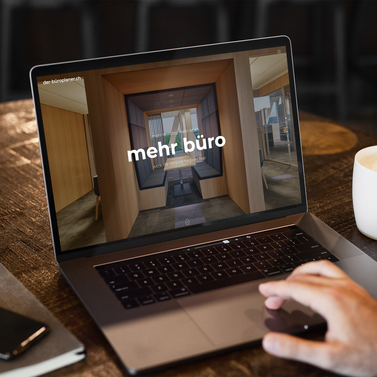 Mann sieht sich die B&uuml;roplaner Webseite ion einem Cafe an. Kaffee steht auf dem Tisch neben Laptop und Handy.