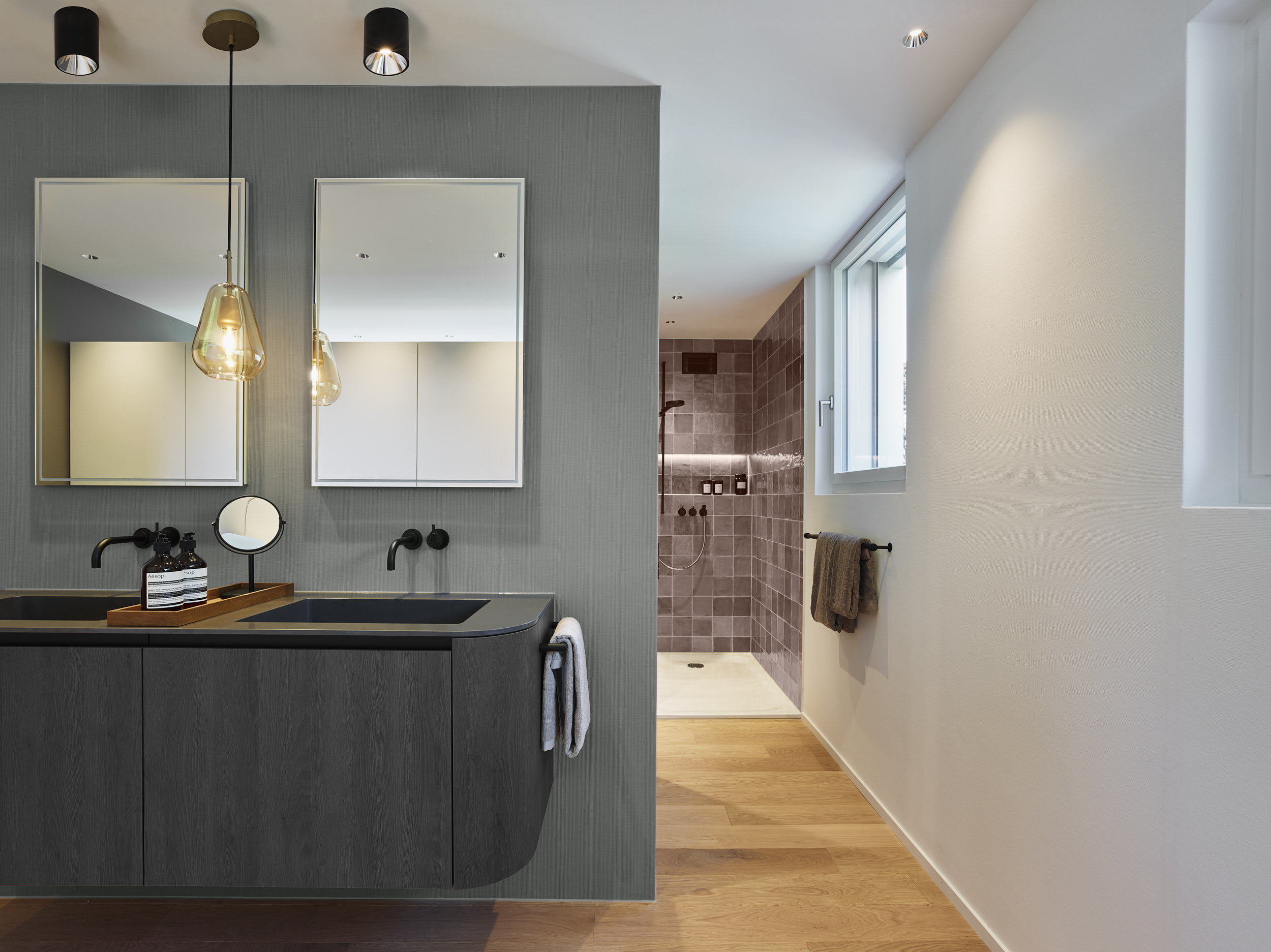 Modernes Bad mit zwei Waschbecken in Anthrazit. Grosses Badezimmer mit lila Platten in der Dusche.