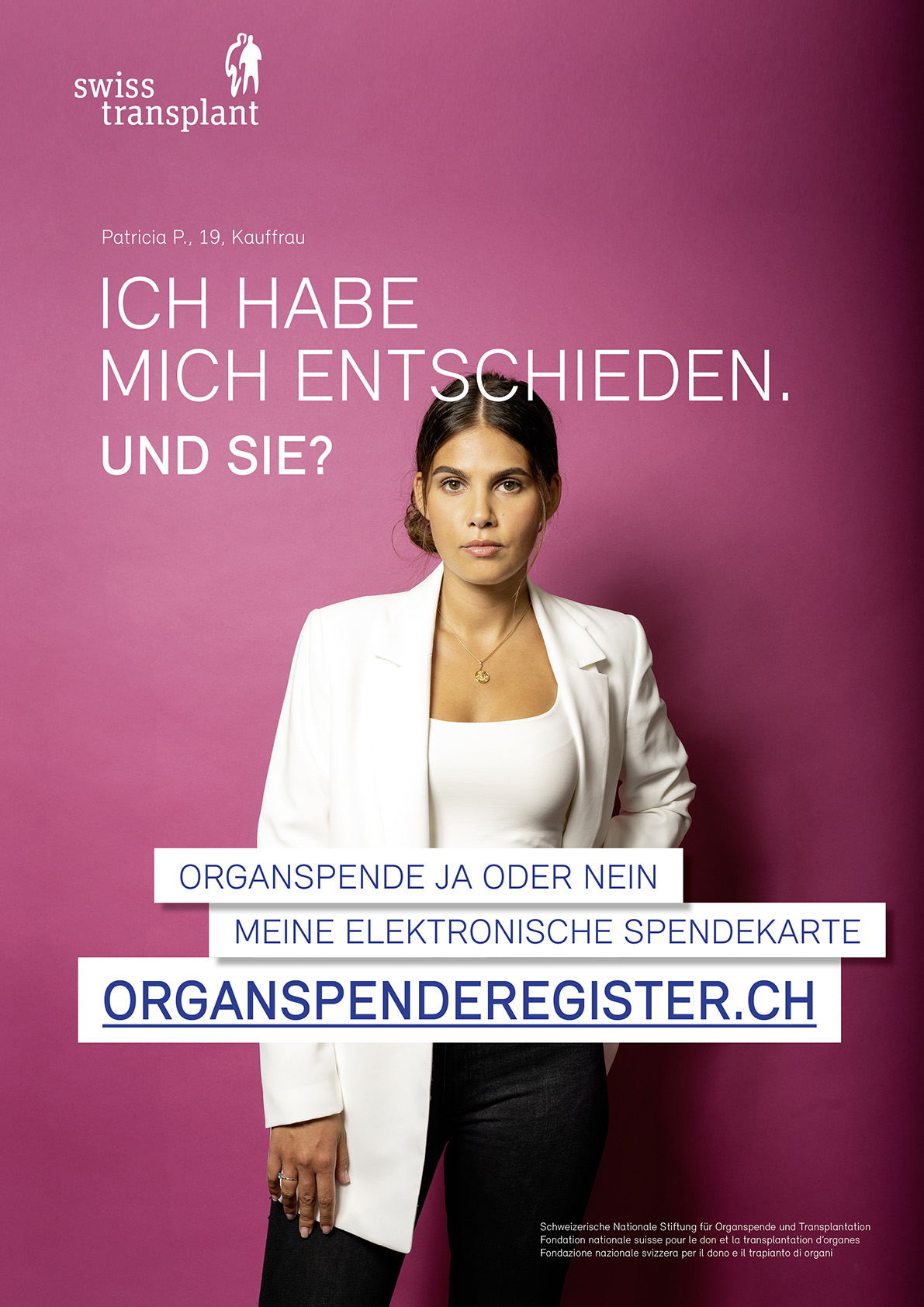 Frau im Anzug steht vor rotvioletter Wand. Statement zur Organspende in Buchbinden. Frau mit weissem Blazer und schwarzer Hose vor buntem Hintergrund.