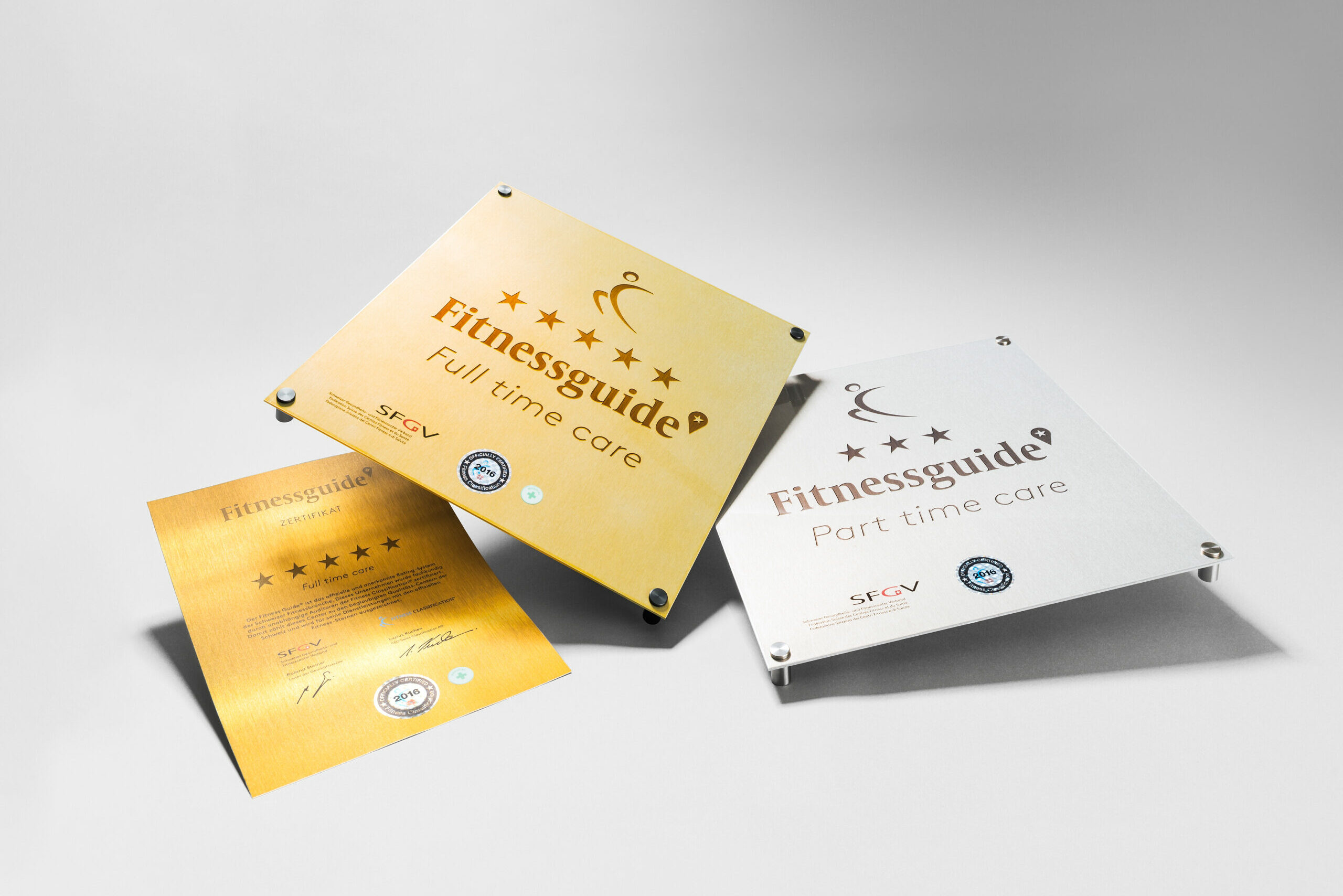 Gold und Silberplaketten Referenz Bilder liegend auf dem Tischfür die Fitnessqualifikation - Fitness Classification Schweiz.