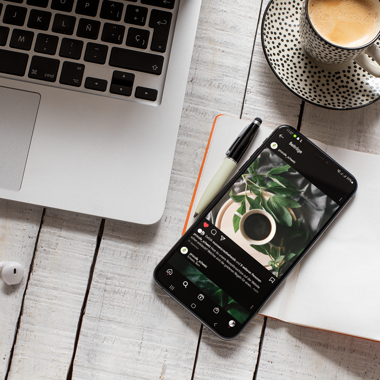 IPhone liegt auf einem Notizbuch auf dem Tisch neben einem MAC Book