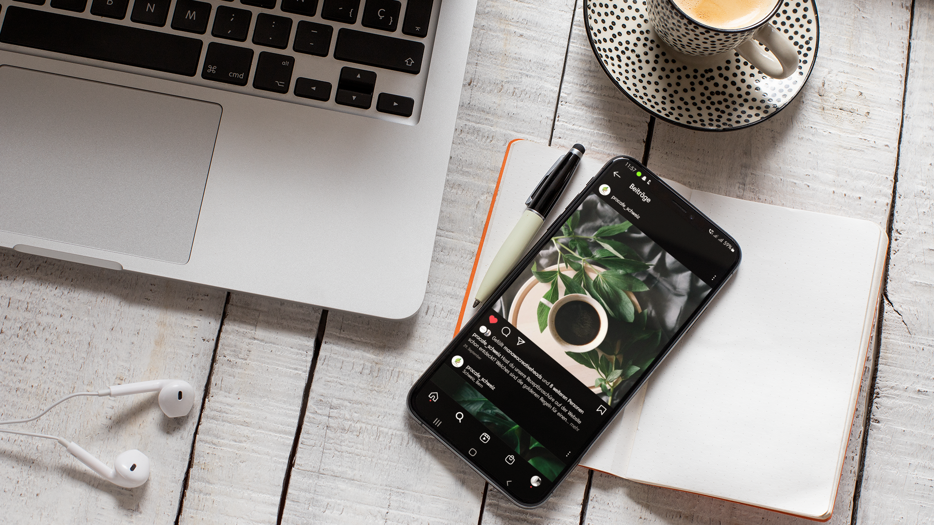 IPhone liegt auf einem Notizbuch auf dem Tisch neben einem MAC Book