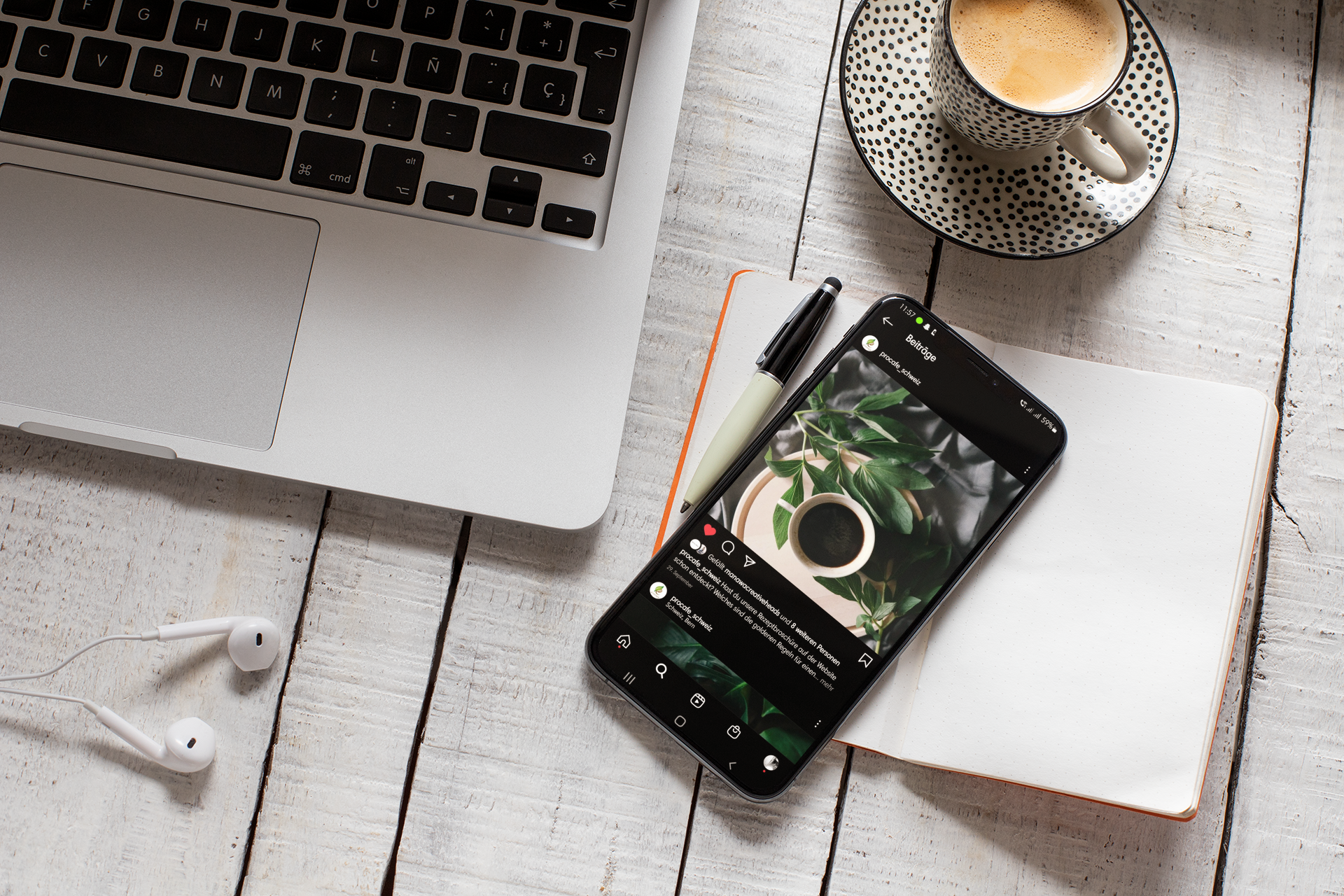 IPhone liegt auf einem Notizbuch auf dem Tisch neben einem MAC Book